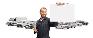 Tamirci beyaz arka planda izole edilmiş bir araç parkında küçük boş bir kart gösteriyor.