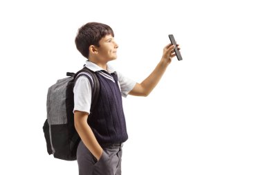 Üniformalı bir öğrenci ayakta duruyor ve beyaz arka planda izole edilmiş bir akıllı telefonu gösteriyor.