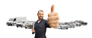 Elinde ingiliz anahtarıyla bir araba parkında tamirci ve beyaz arka planda izole edilmiş baş parmaklar.