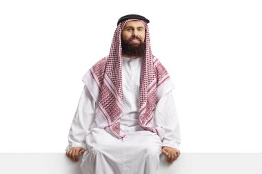 Suudi Arabistan 'lı bir adam panelde oturuyor ve beyaz arka planda izole edilmiş kameraya bakıyor.