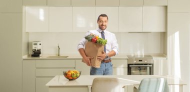 Mutfakta poşet tutan bir adam.