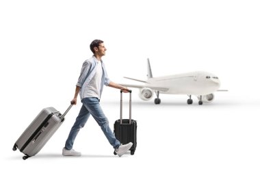 Havaalanında beyaz arka planda iki bavul taşıyan bir gencin tam boy profil fotoğrafı.