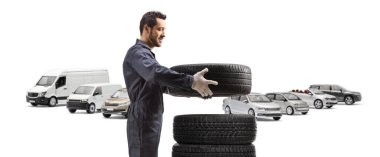 Otomobil tamircisi beyaz arka planda izole edilmiş bir otoparkta araba lastiklerini ayırıyor.