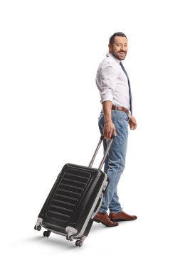 Adam bavulu çekiyor ve beyaz arka planda izole edilmiş kameraya bakıyor.