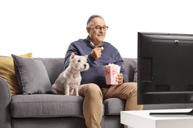 Yetişkin adam ve köpek televizyon izliyor ve beyaz arka planda izole edilmiş patlamış mısır yiyor.