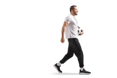 Futbol koçu, beyaz sırtüstü yürüyen ve bir top taşıyor.