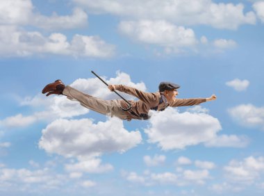 Yaşlı bir adam elinde bastonla gökyüzünde uçuyor.