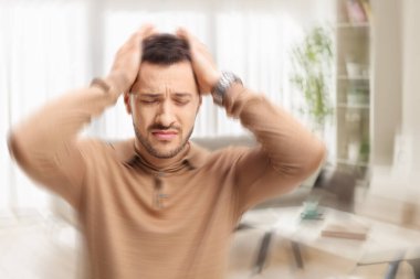 Baş dönmesi ve baş ağrısı çeken genç bir adam.