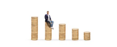 Beyaz arka planda izole edilmiş madeni para, finans ve ekonomi konsepti üzerinde oturan genç adam