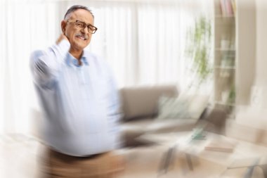 Servikal baş dönmesi olan olgun bir adam bir odada duruyor.