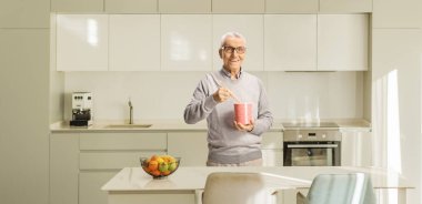 Yaşlı bir adam mutfakta bir kutu erişte tutuyor.