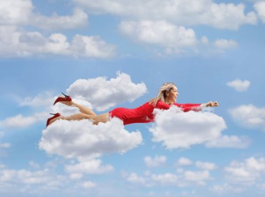 Gökyüzünde uçan kırmızı elbiseli çekici bir kadın.