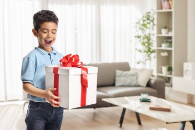 Hoş Asyalı çocuk evde büyük bir hediye kutusuna bakıyor.