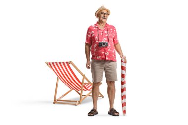 Plaj şemsiyesi tutan ve beyaz arka planda izole bir plaj sandalyesinin yanında duran bir adam.