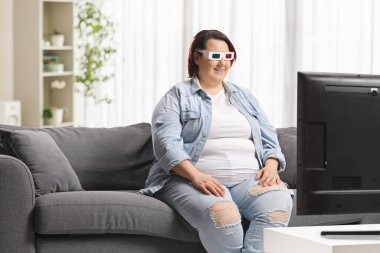 Kanepede oturan ve akıllı bir TV 'de 3D film izleyen bir kadın.