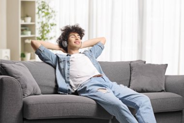 Adam kanepede dinleniyor ve müzik dinliyor. 