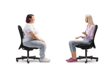 Sandalyede oturan zayıf bir kadın beyaz arka planda izole edilmiş şişman bir kadınla konuşuyor.