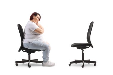 Beyaz arka planda, boş bir ofis sandalyesinin karşısında oturan düşünceli şişman kadın.