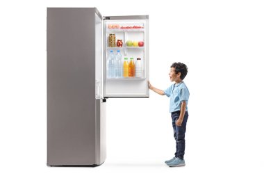 Beyaz arka planda izole edilmiş buzdolabı açan bir çocuğun tam boy profil çekimi.