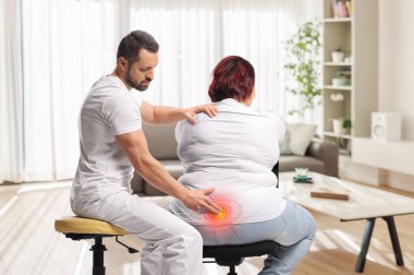 Kayropraktik uzmanı sırtında ağrı olan kilolu bir kadını tedavi ediyor.