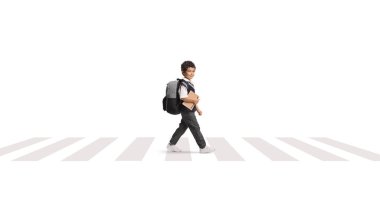 Üniformalı Asyalı bir öğrenci zebra geçidinde yürüyor ve beyaz arka planda izole edilmiş bir kitap tutuyor.