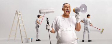 Bir silindir ve megafon tutan bir ressam ve beyaz arka planda izole edilmiş bir duvarı boyayan işçiler.