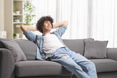 Evdeki kanepede oturan rahat genç adam.