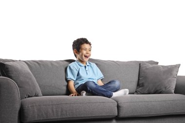 Çocuk kanepede oturuyor ve beyaz arka planda izole bir şekilde gülüyor.