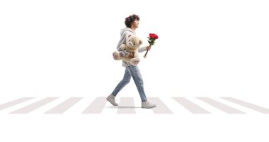 Beyaz arka planda ayıcık ve kırmızı güllerle karşıdan karşıya geçen bir adamın tam boy profil fotoğrafı.