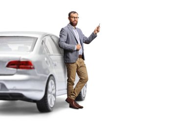 Sürücü arabaya yaslanıyor ve elinde beyaz arka planda izole edilmiş bir anahtar tutuyor.