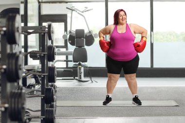 Boks eldivenli şişman bir kadın spor salonunda dikiliyor.