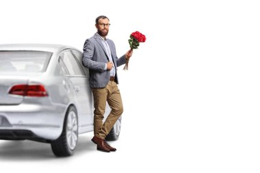 Arabaya yaslanan ve beyaz arka planda izole edilmiş kırmızı güller tutan bir adam.