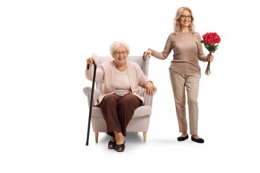 Yaşlı anne ve kızı beyaz arka planda bir demet kırmızı gül tutuyor.