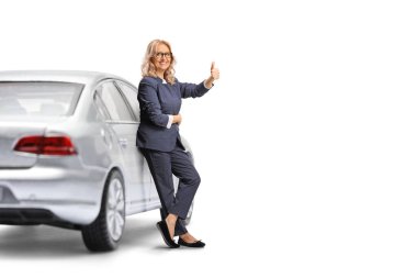 Kadın sürücü arabaya yaslanıyor ve işaret ediyor beyaz arka planda izole edilmiş.