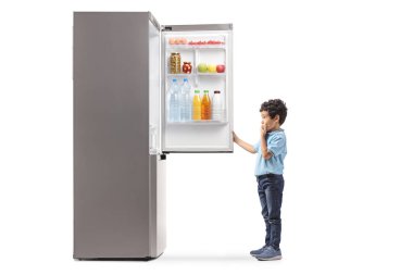 Buzdolabına bakan ve beyaz arka planda soyutlanmış bir çocuğun tam boy profil çekimi.