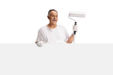 Duvarın arkasında beyaz arka planda izole edilmiş boya silindiri tutan bir ressam.