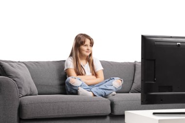 Kanepede oturan ve beyaz arka planda izole edilmiş televizyon izleyen bir kız.