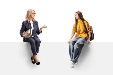 Panelde oturan bir kadın elinde bir kitapla beyaz arka planda izole edilmiş genç bir kız öğrenciyle konuşuyor.