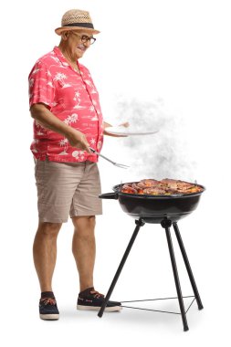 Elinde tabak ve çatallı et olan bir adam beyaz arka planda izole edilmiş bir bbq üzerinde ızgara yapıyor.