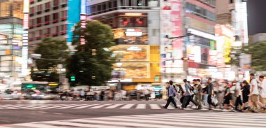 Panning shot of people crossing the famous Shibuya Crossing in Tokyo at night
