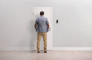 Dairenin kapısında dikilen bir adamın arka görüntüsü.