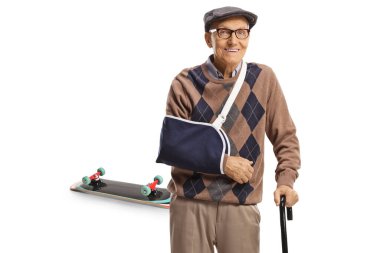 Kırık kollu yaşlı bir adam alçı takıyor ve elinde bir değnekle kaykayın önünde duruyor.