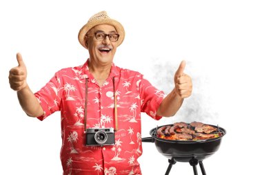 Kameralı mutlu erkek turist beyaz arka planda izole edilmiş bir bbq 'ın önünde baş parmak hareketi yapıyor.