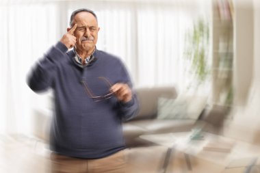 Olgun adam gözlük tutuyor ve evde sersemlemiş ve başı dönüyor.