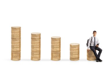 Kitapları olan üniversite öğrencisi beyaz arka planda izole edilmiş madeni paraların üzerinde oturuyor.