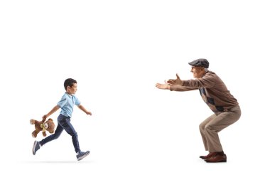 Dedesine sarılmak için koşan ve beyaz arka planda izole edilmiş bir oyuncak ayı taşıyan bir çocuğun tam boy profil çekimi.