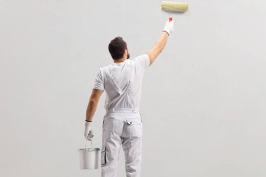 Kovayı tutan ve duvarı boyayan ressam. 