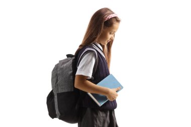 Okul üniformalı üzgün bir kız öğrenci beyaz arka planda izole bir kitap tutuyor ve yürüyor.