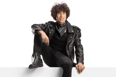 Deri ceketli genç adam beyaz arka planda boş bir panelde oturuyor.