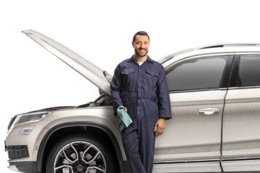 Araba tamircisi beyaz arka planda kaputu açık bir araca yaslanıyor.